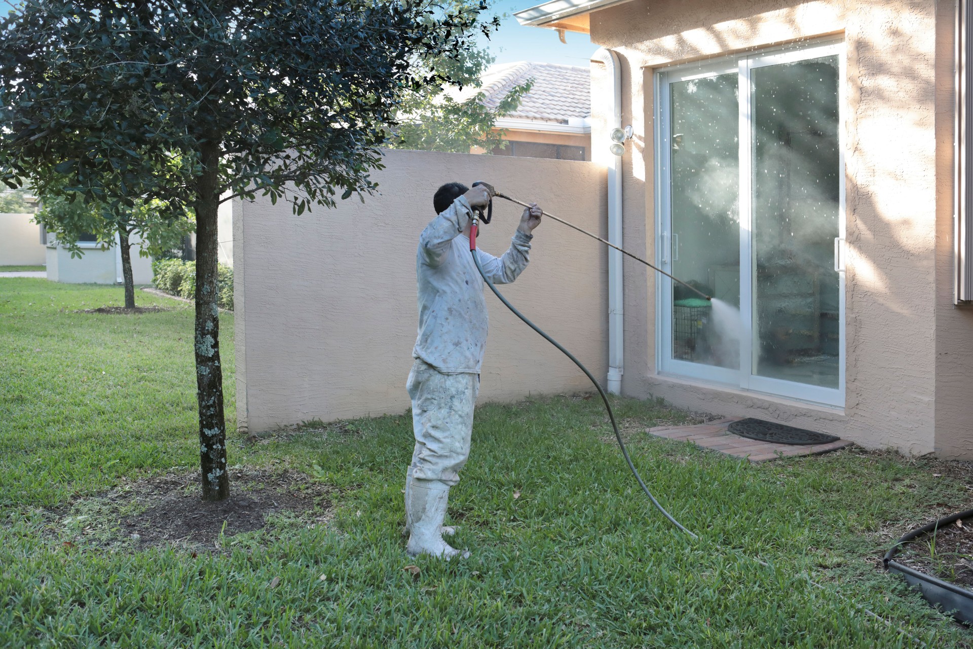 Series:Hispanic male house worker power washing back of upscale home